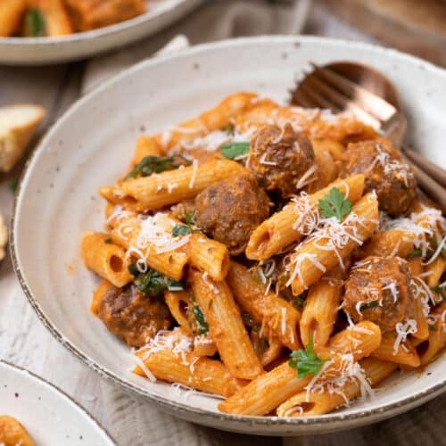 a bowl of sausage pasta topped with cheese.