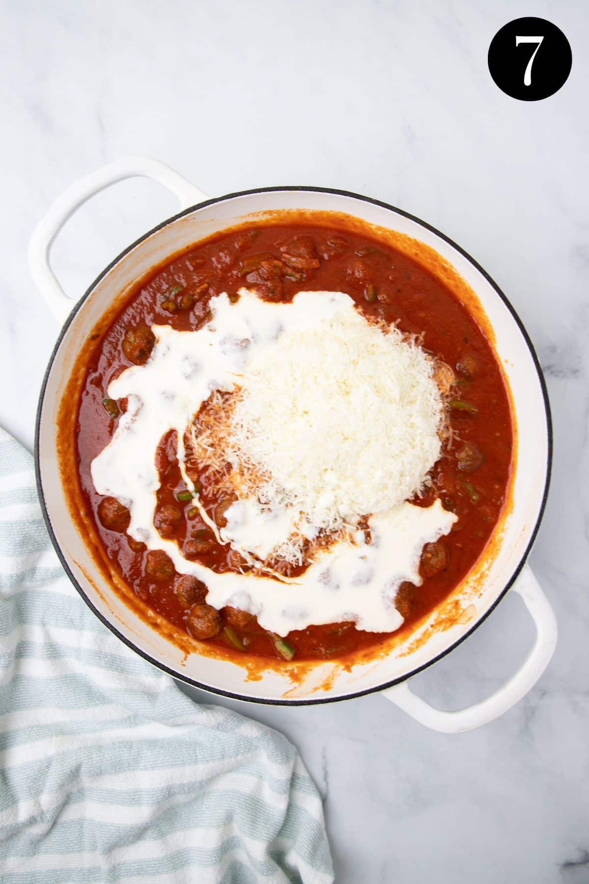 cream and cheese added to tomato sauce in a pan.