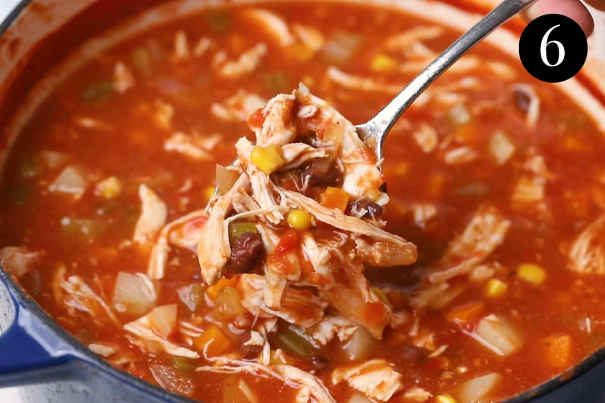 A spoon with Mexican soup, chicken and vegetables.