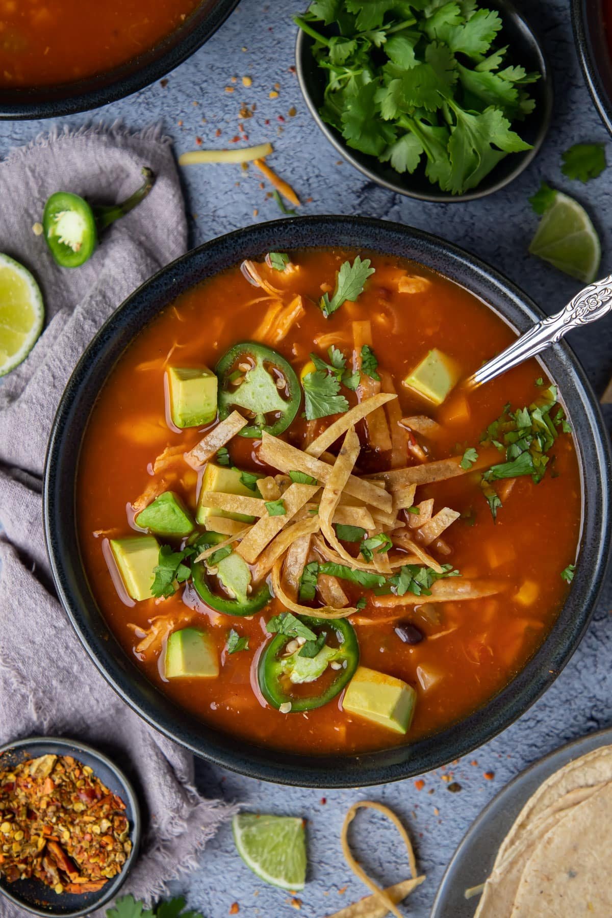 a bowl of soup topped with avocado and tortillas.