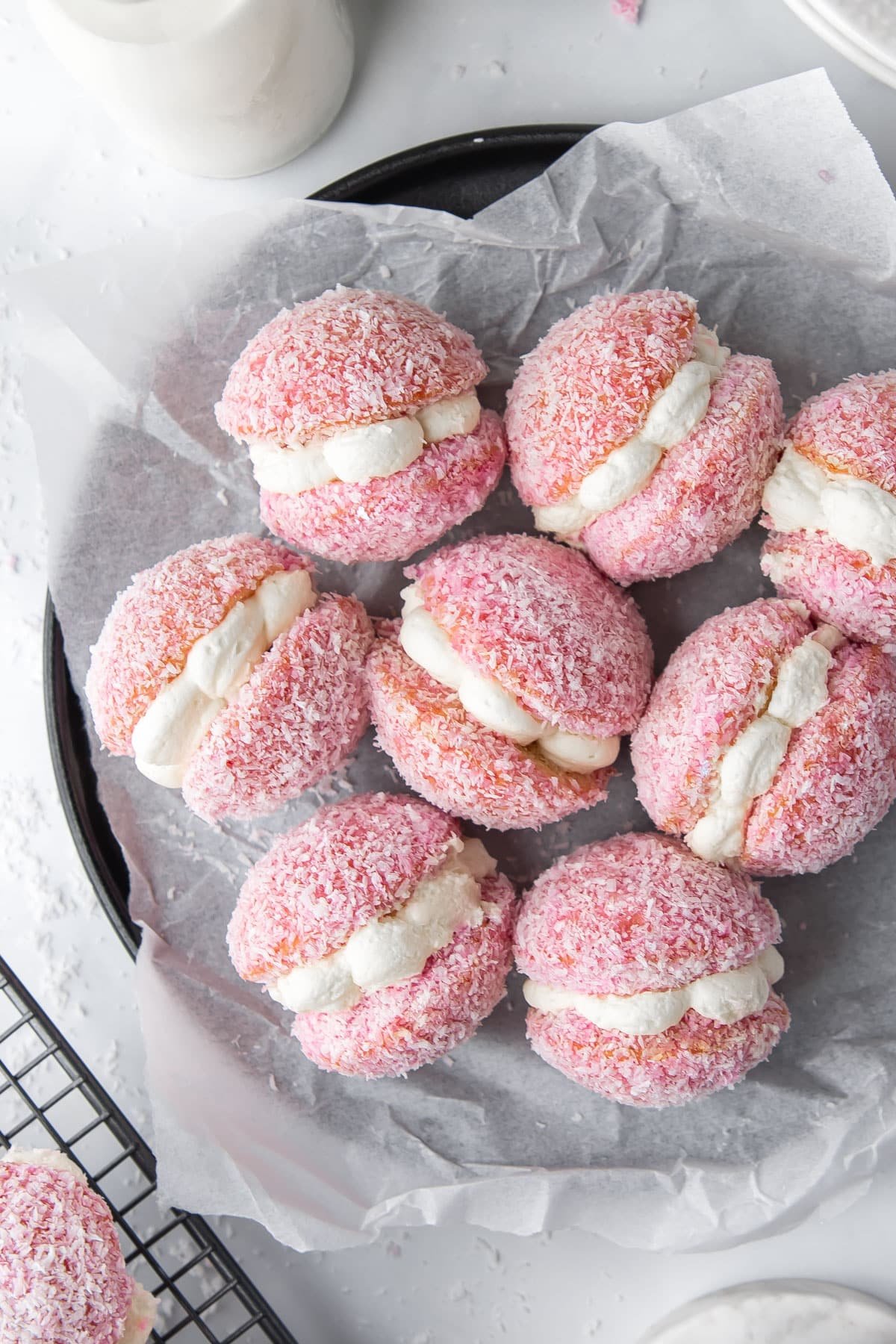 pink jelly cakes coated in coconut, on a black plate.