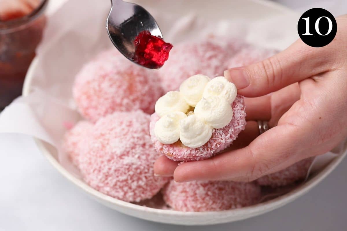 hands adding jelly to a cake topped with cream.