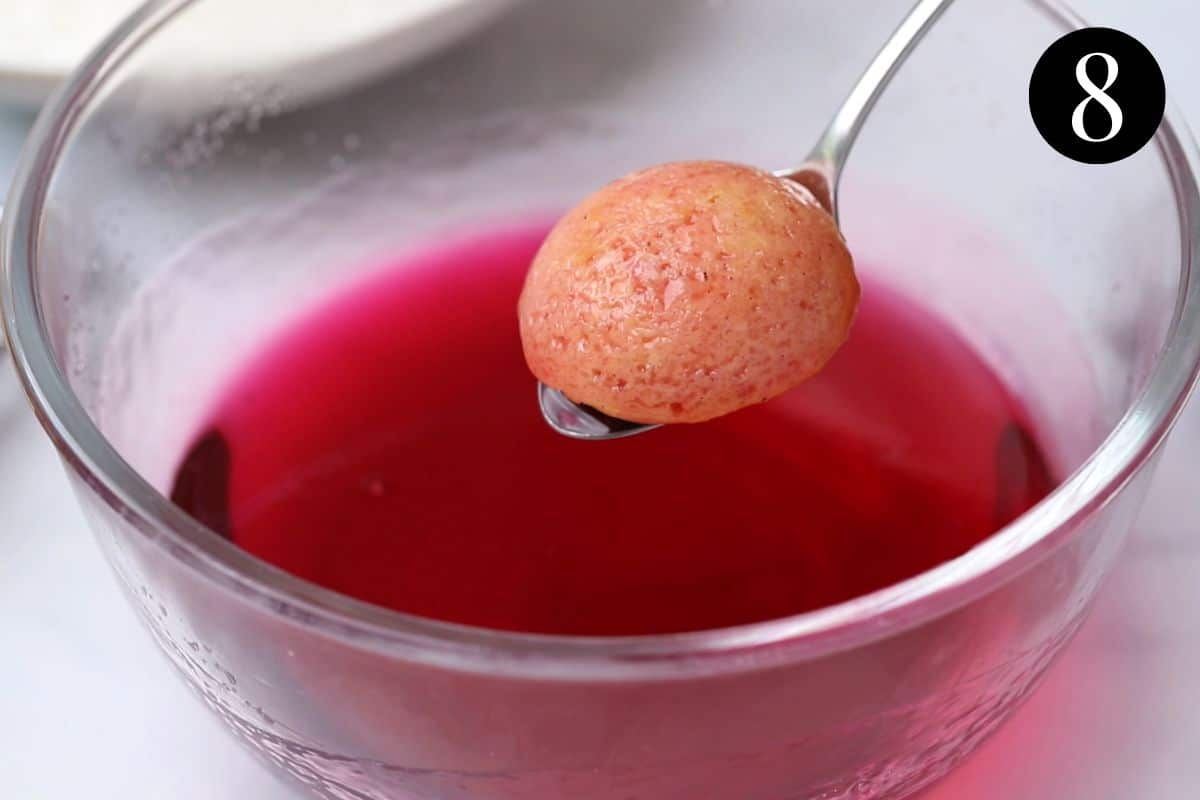 a spoon holding a cake, soaked in jelly.