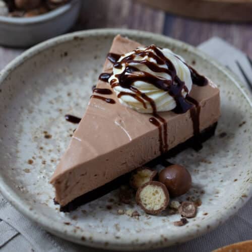 a slice of chocolate cheesecake on a plate topped with cream.