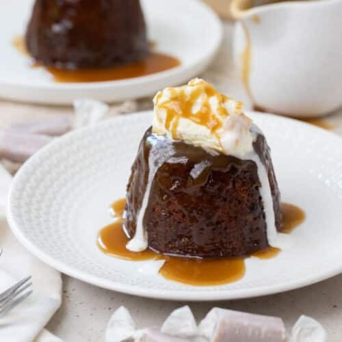 a sticky date pudding on a plate with cream and caramel sauce.