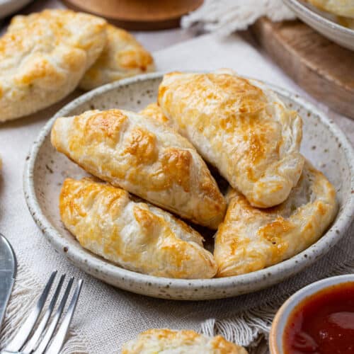 pasties on a plate with tomato sauce and cutlery.