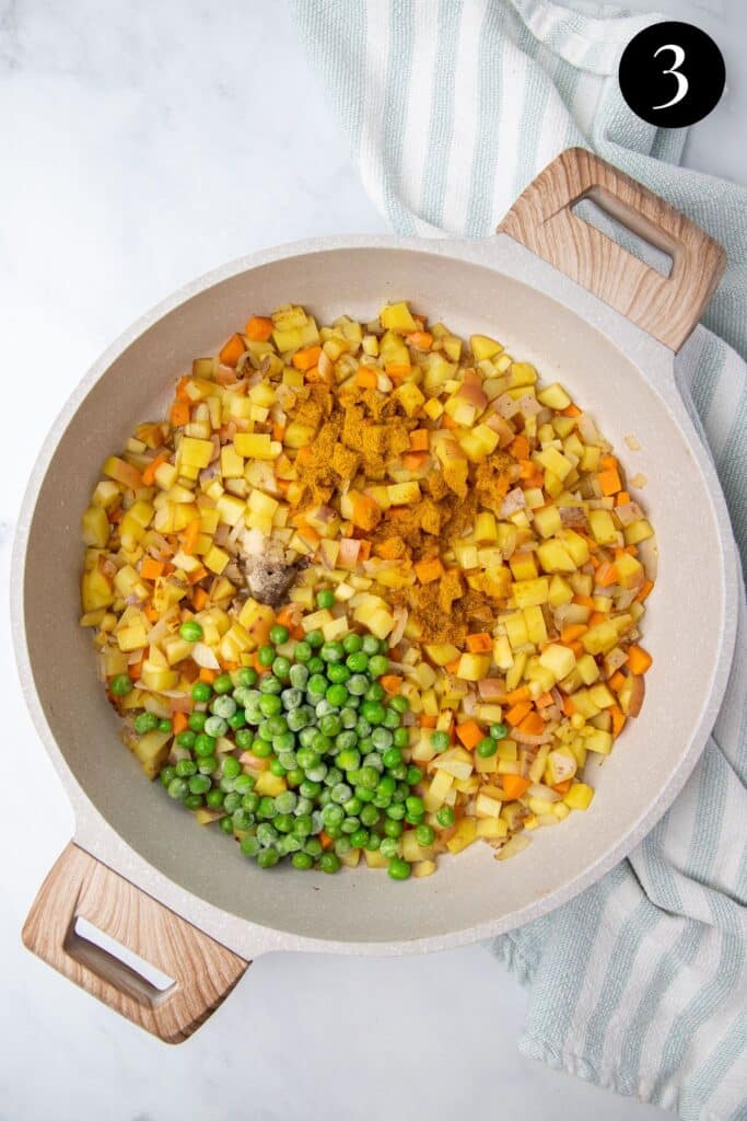 peas and curry powder added to vegetables in a pan.