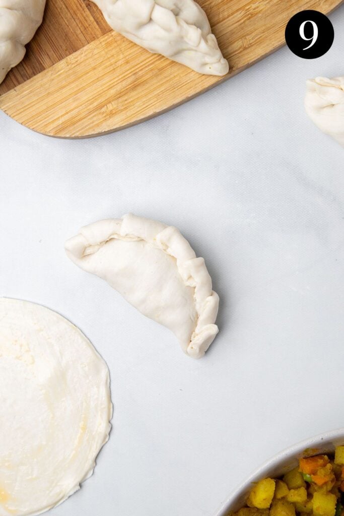 filled pastry folded into a pasty on a white table.