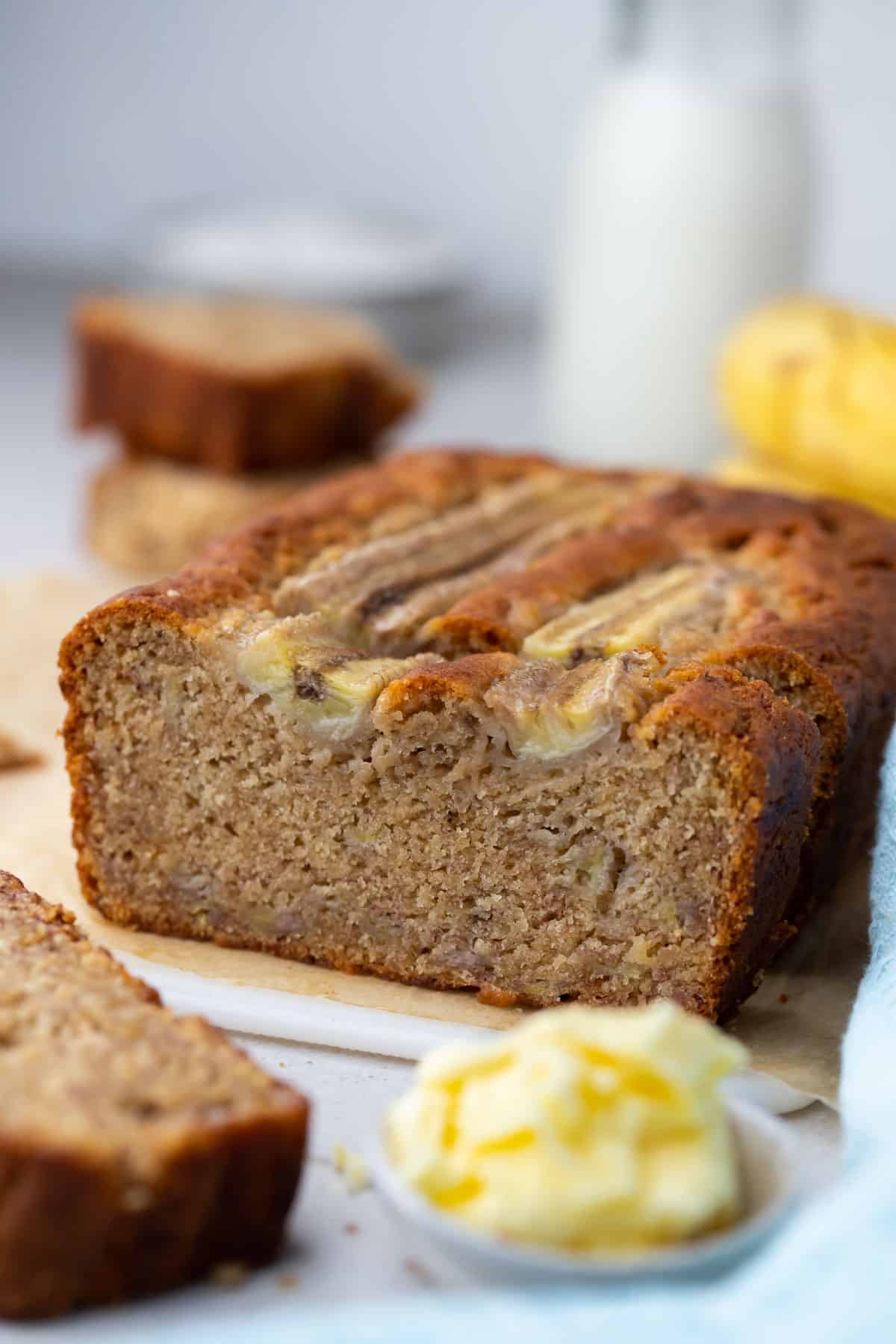 a loaf of banana bread on a bench, with butter.