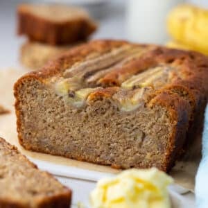 a loaf of banana bread cut into slices on a bench.