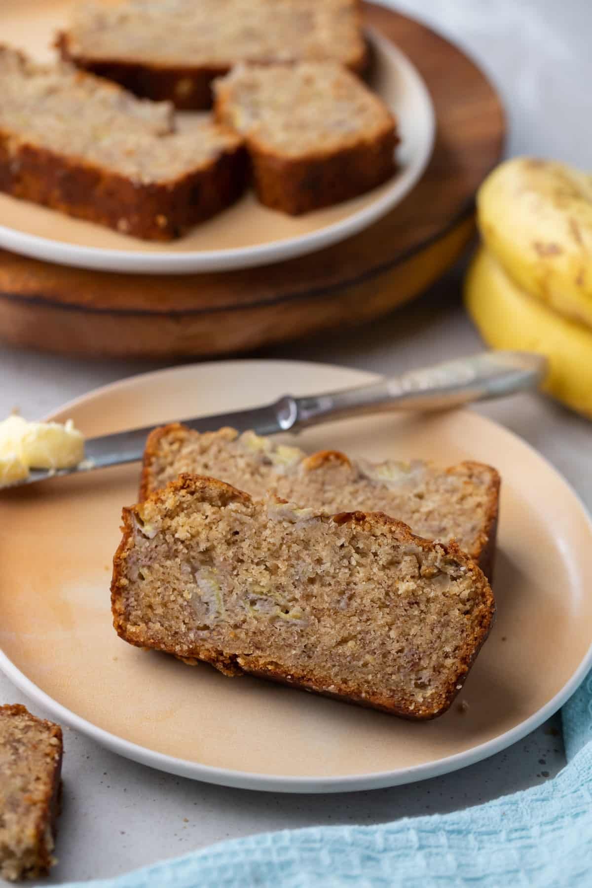 two slices of banana bread on a plate with a butter knife.