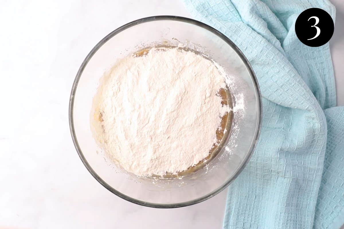 flour added to mashed banana mixture in a bowl.