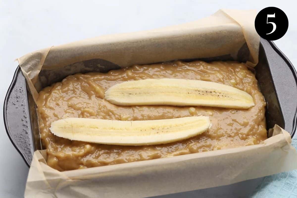 batter in a loaf tin, topped with two pieces of sliced banana.