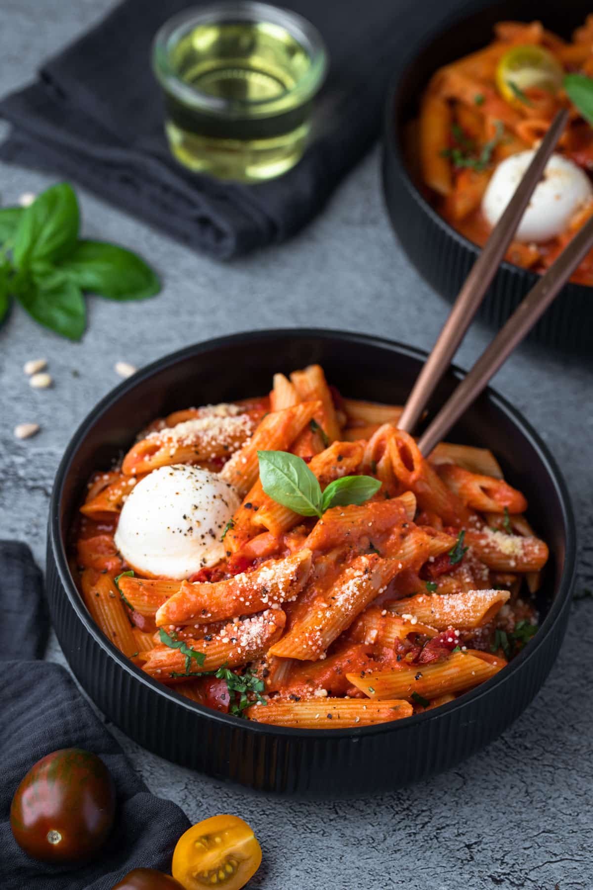 a bowl of tomato pasta topped with basil and cheese.
