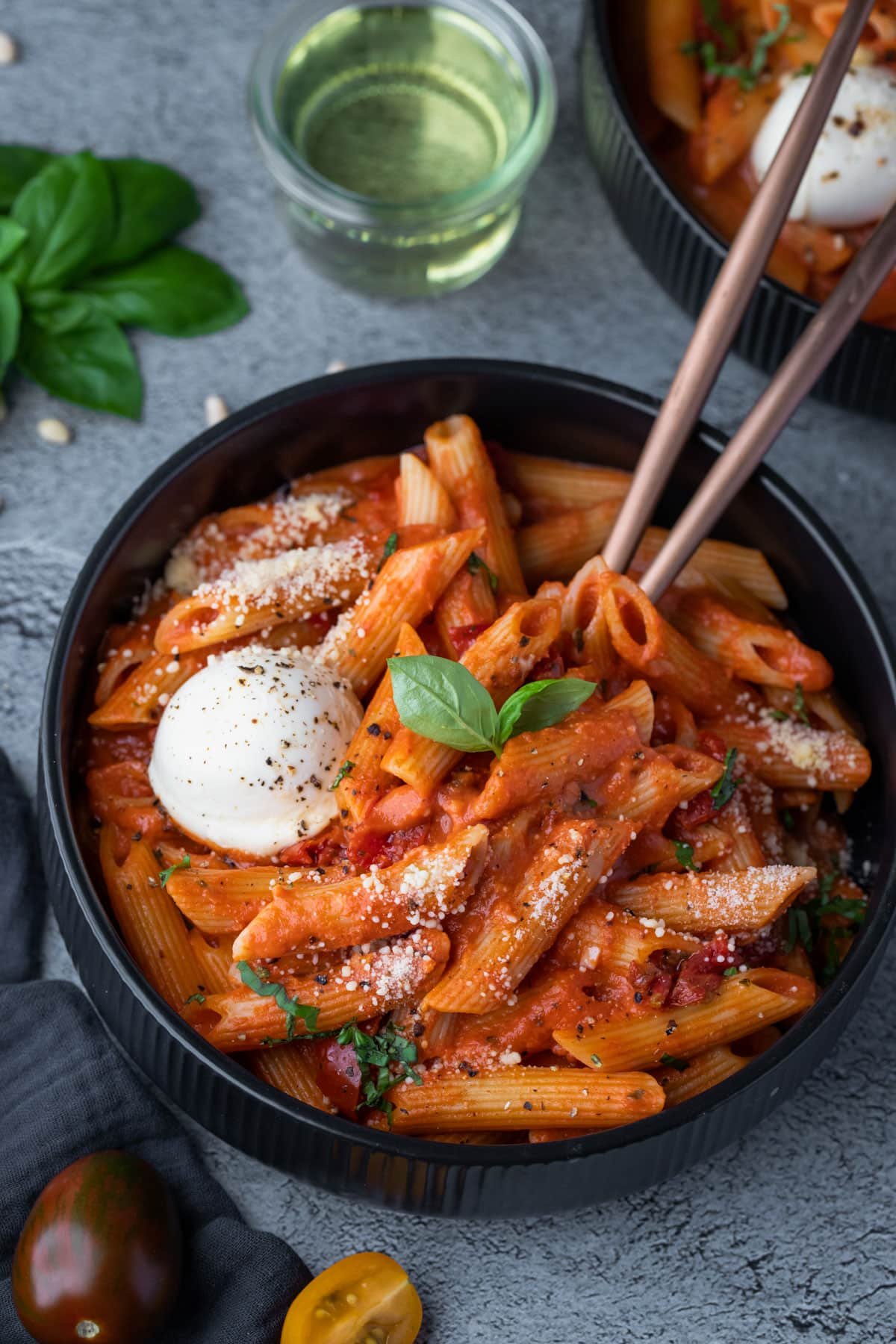 a bowl of tomato pasta topped with basil leaves.