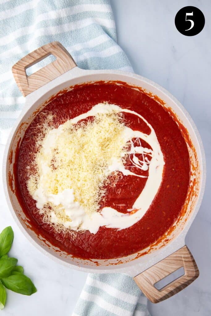 tomato sauce in a pot topped with cream and parmesan.
