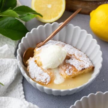 lemon delicious pudding in a bowl, topped with a scoop of ice cream.