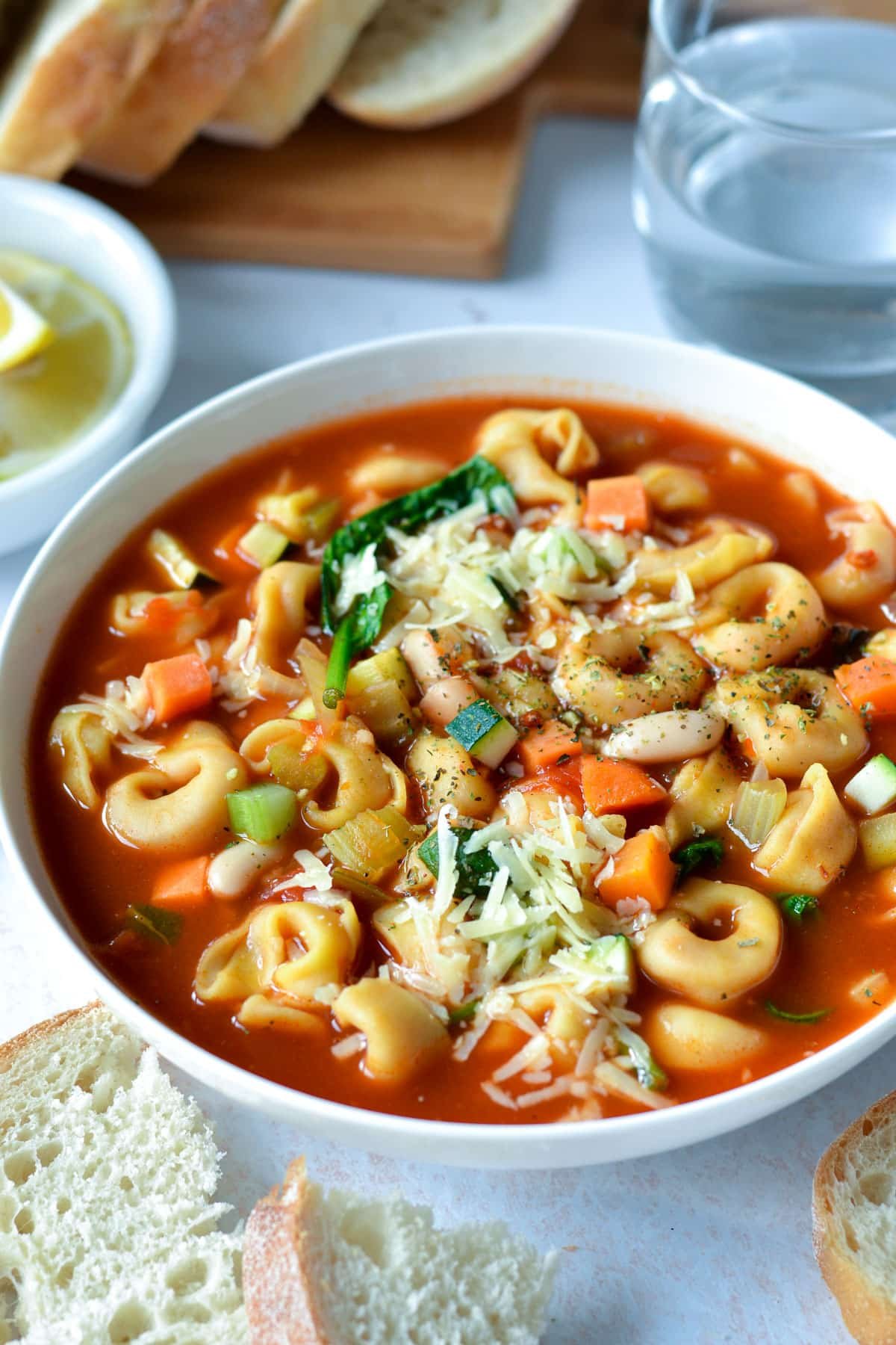 a bowl of soup topped with cheese and tortellini.