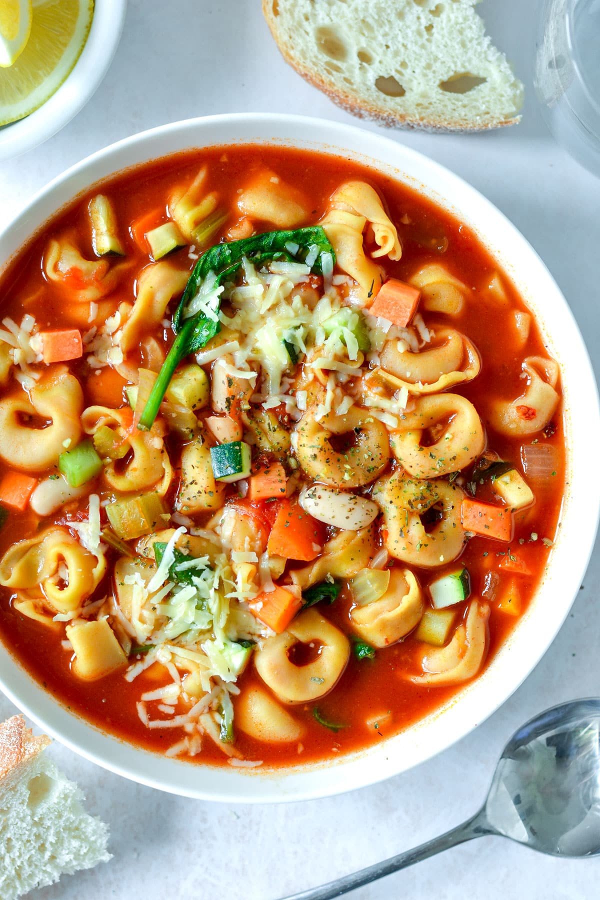 vegetable soup filled with tortellini and topped with cheese.