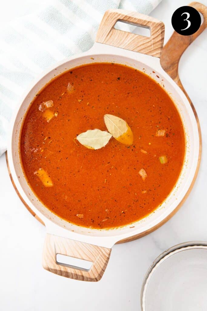 tomato soup in a pot with a bay leaf.