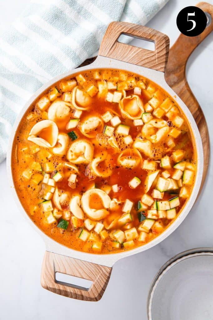 tortellini and zucchini cooking in soup.