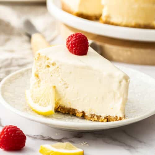 a slice of cheesecake on a plate, with lemon and fresh berries.