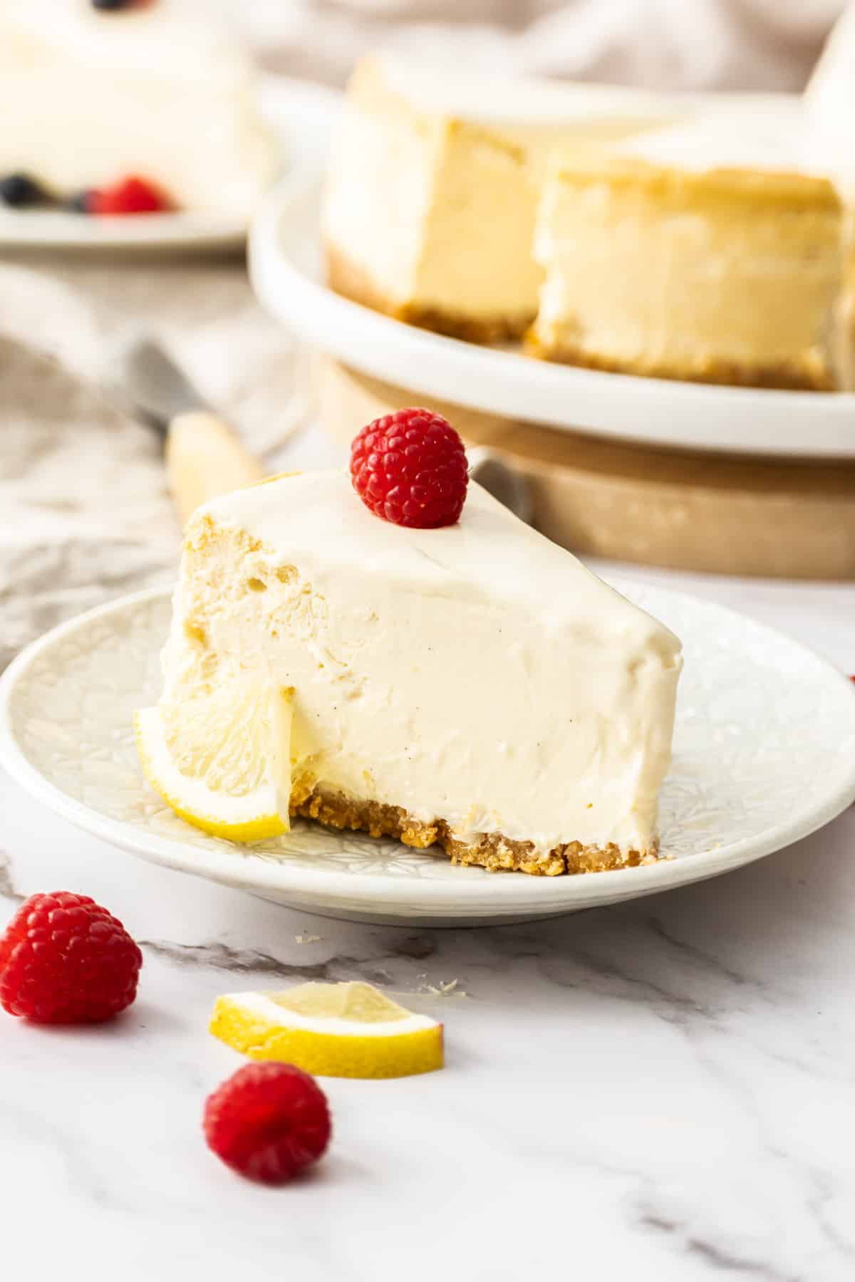 a slice of cheesecake on a plate, topped with raspberries.