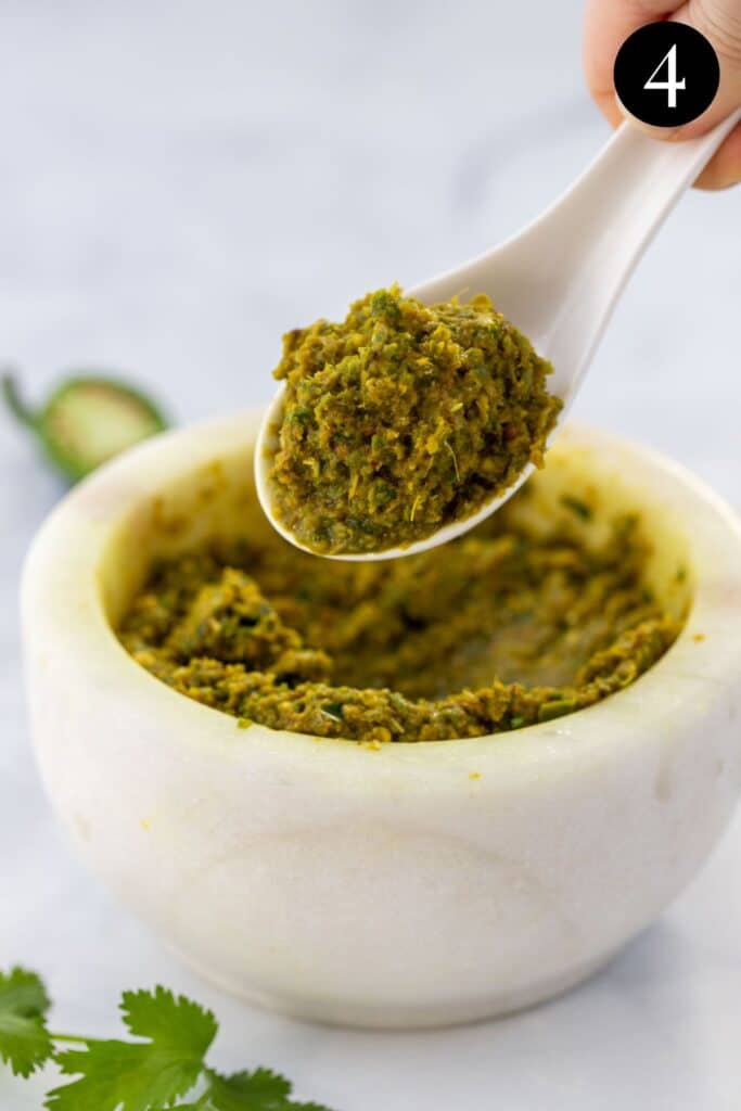 a spoon holding a portion of green curry paste.