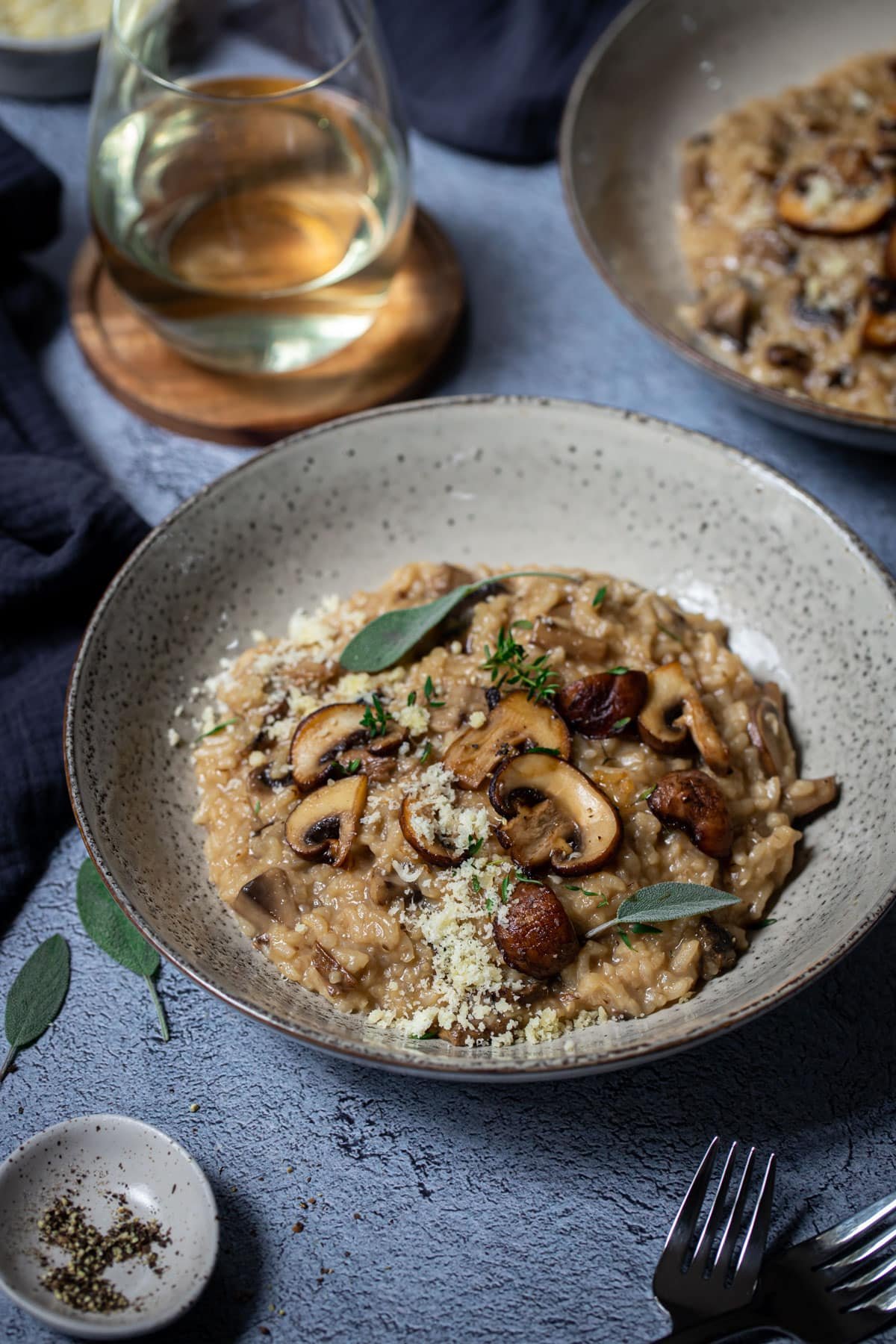 a bowl of risotto on a table, topped with sliced mushrooms and herbs.