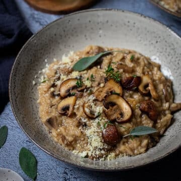 a bowl of risotto, topped with mushrooms and herbs.