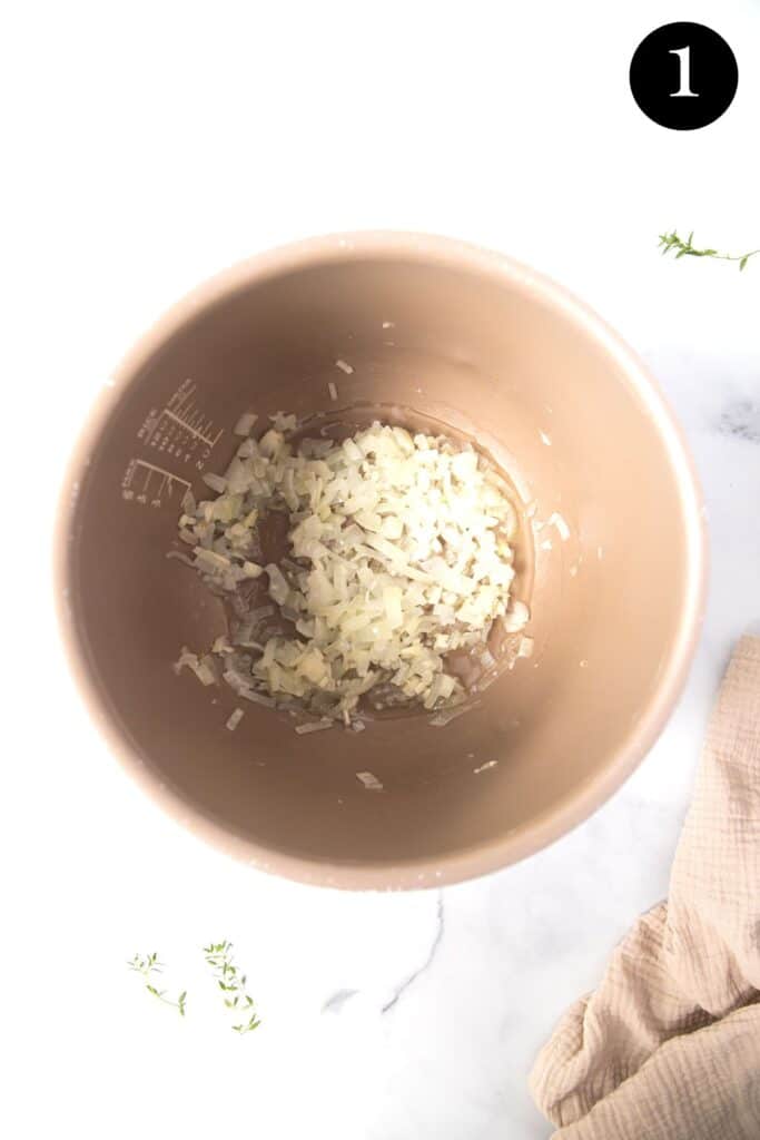 onion and garlic sauteeing in a slow cooker pot.