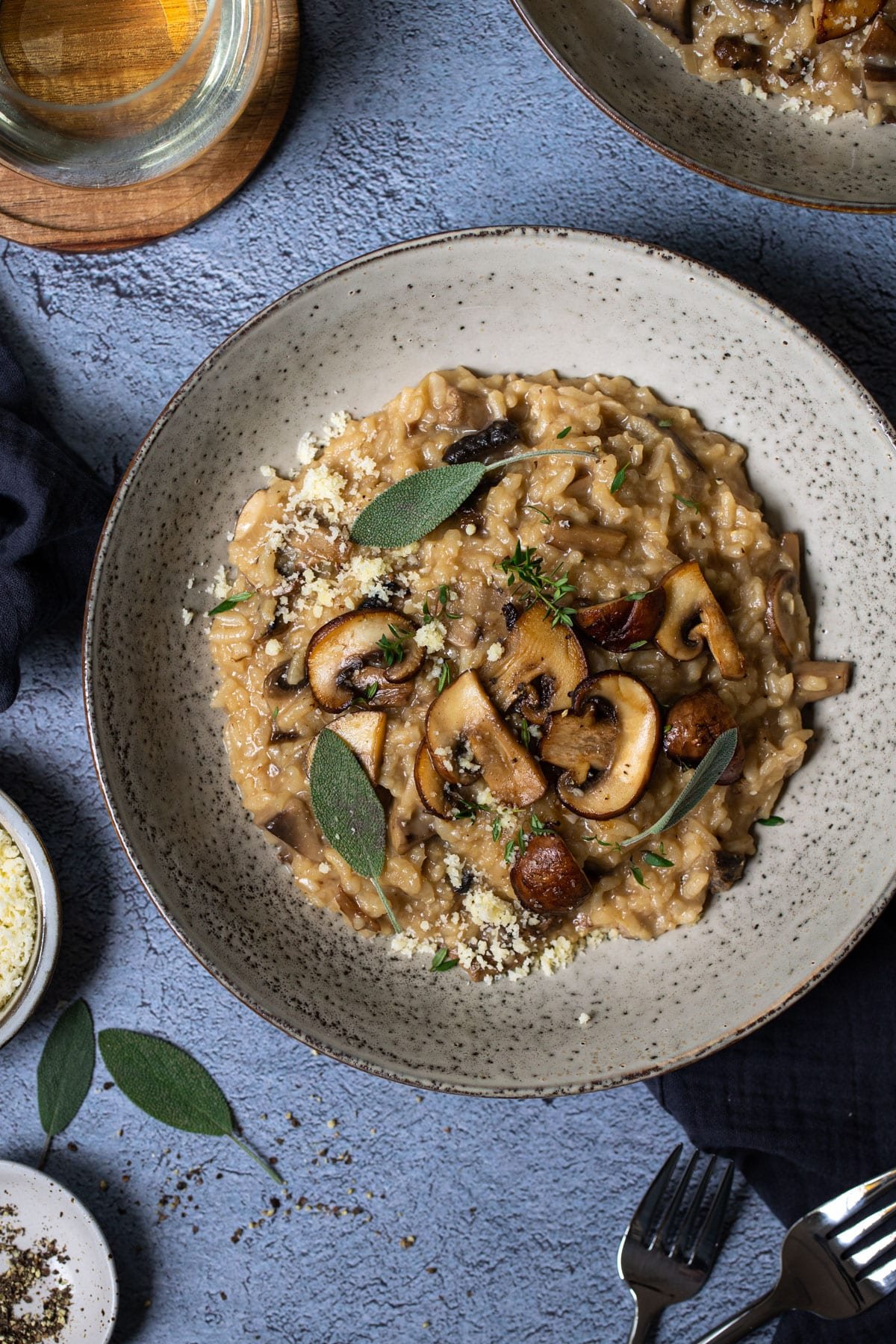 a bowl of risotto, topped with cheese, mushrooms and herbs.