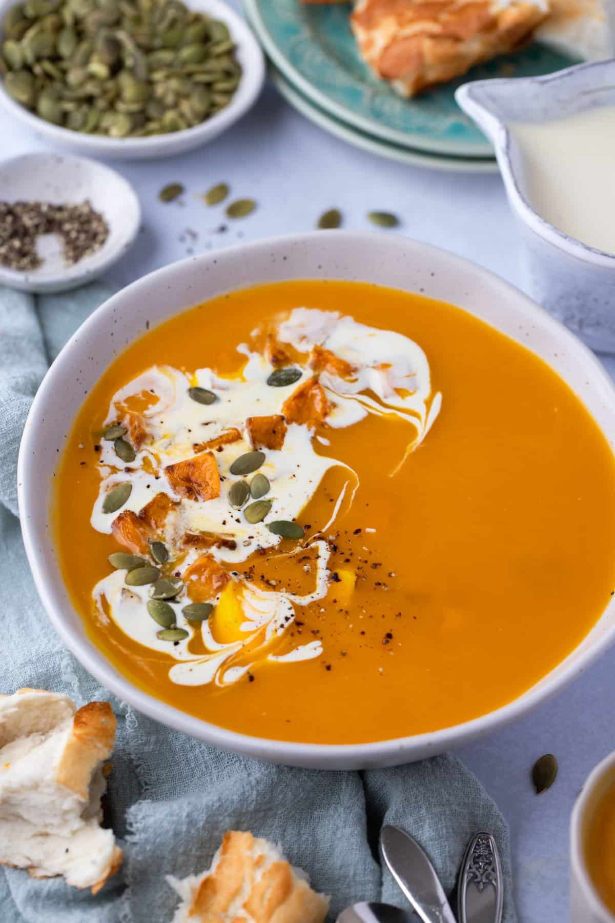 a bowl of soup topped with a swirl of cream and pumpkin seeds.