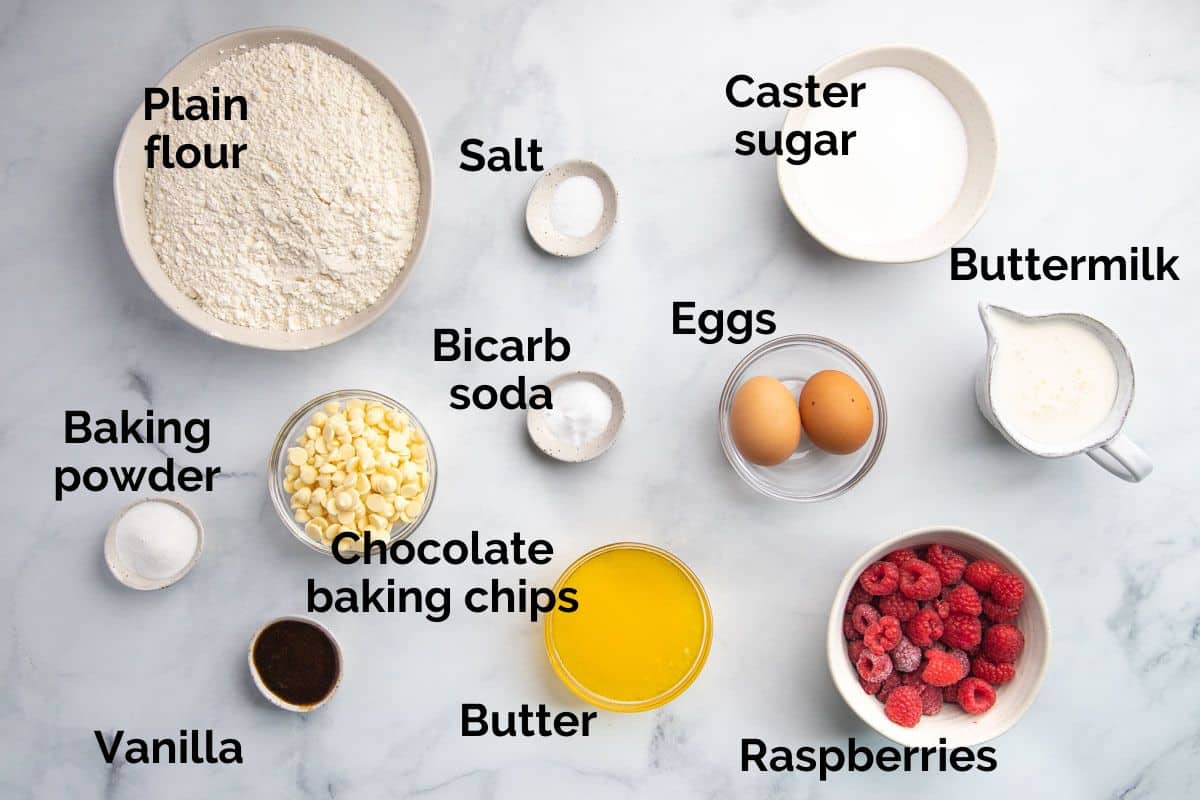 all ingredients for raspberry and white chocolate muffins, laid out on a table.