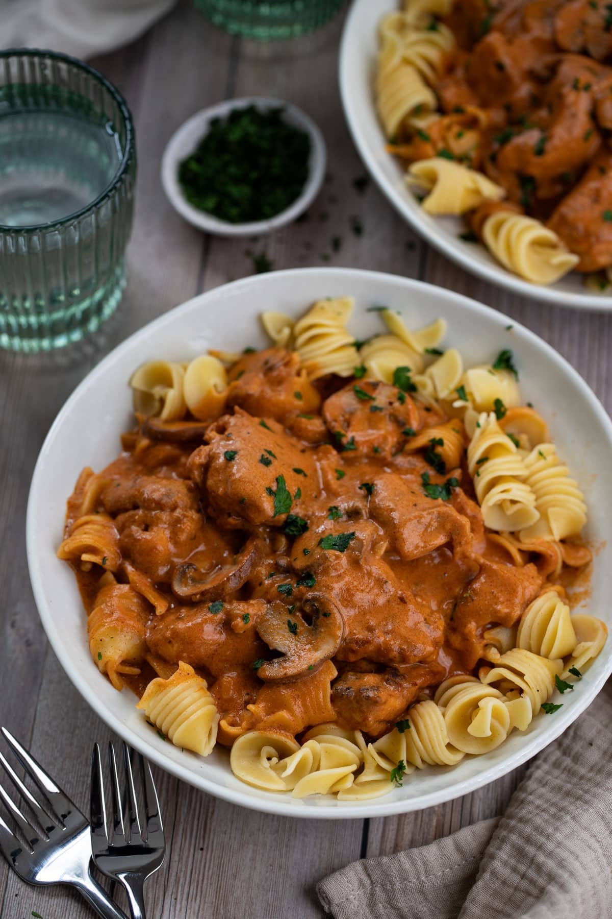 a bowl of chicken stroganoff and pasta, on a table.