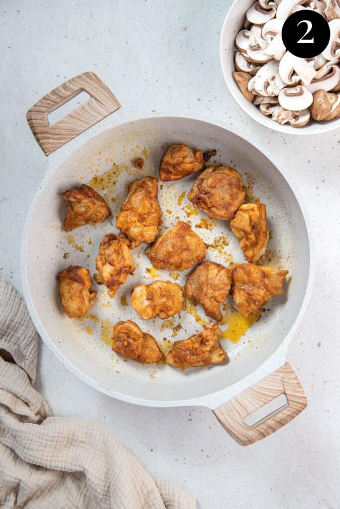 pieces of chicken browning in a pan.