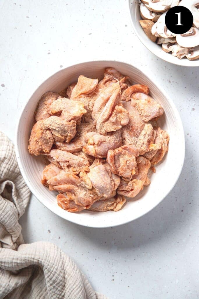 a bowl with pieces of chicken, coated in flour and spices.