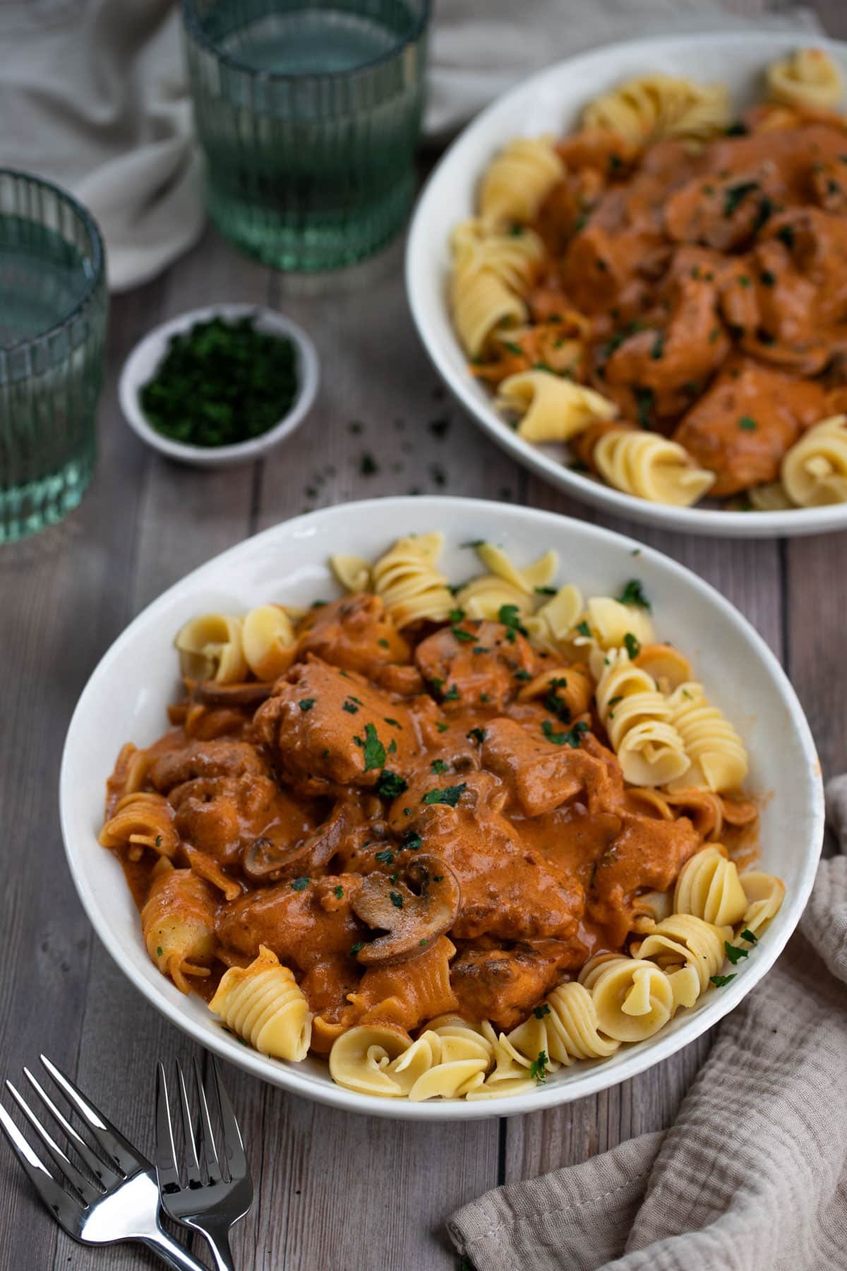 bowls of chicken stroganoff and pasta on a table.