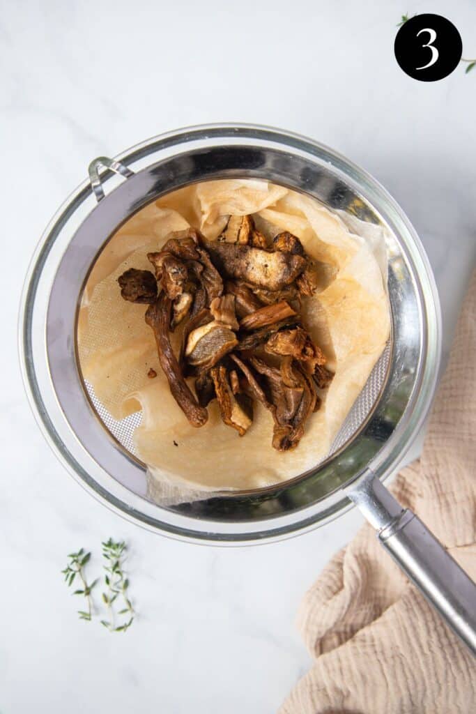 porcini mushrooms in a strainer lined with paper towel.