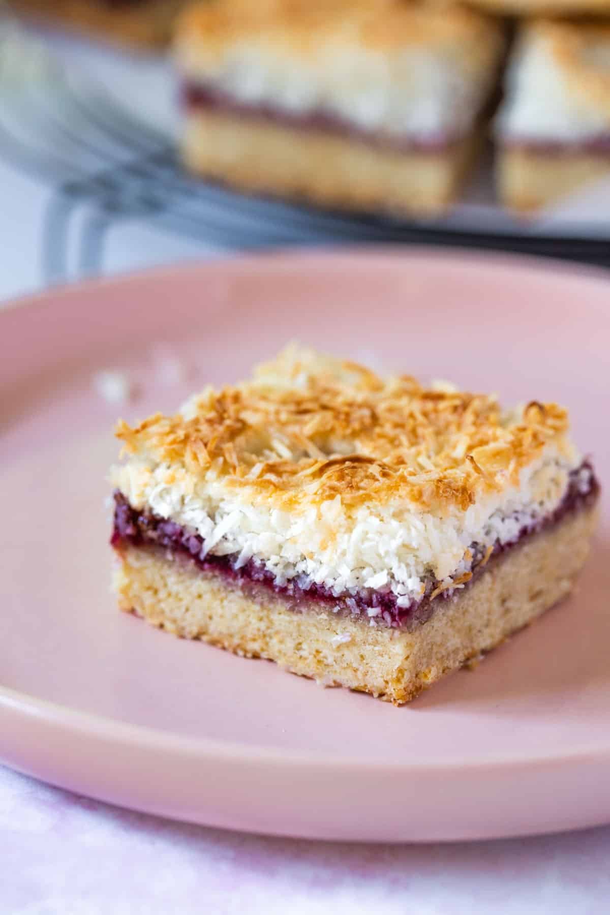 a piece of coconut jam slice on a plate.