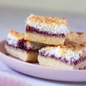 pieces of raspberry coconut slice, arranged on a plate.