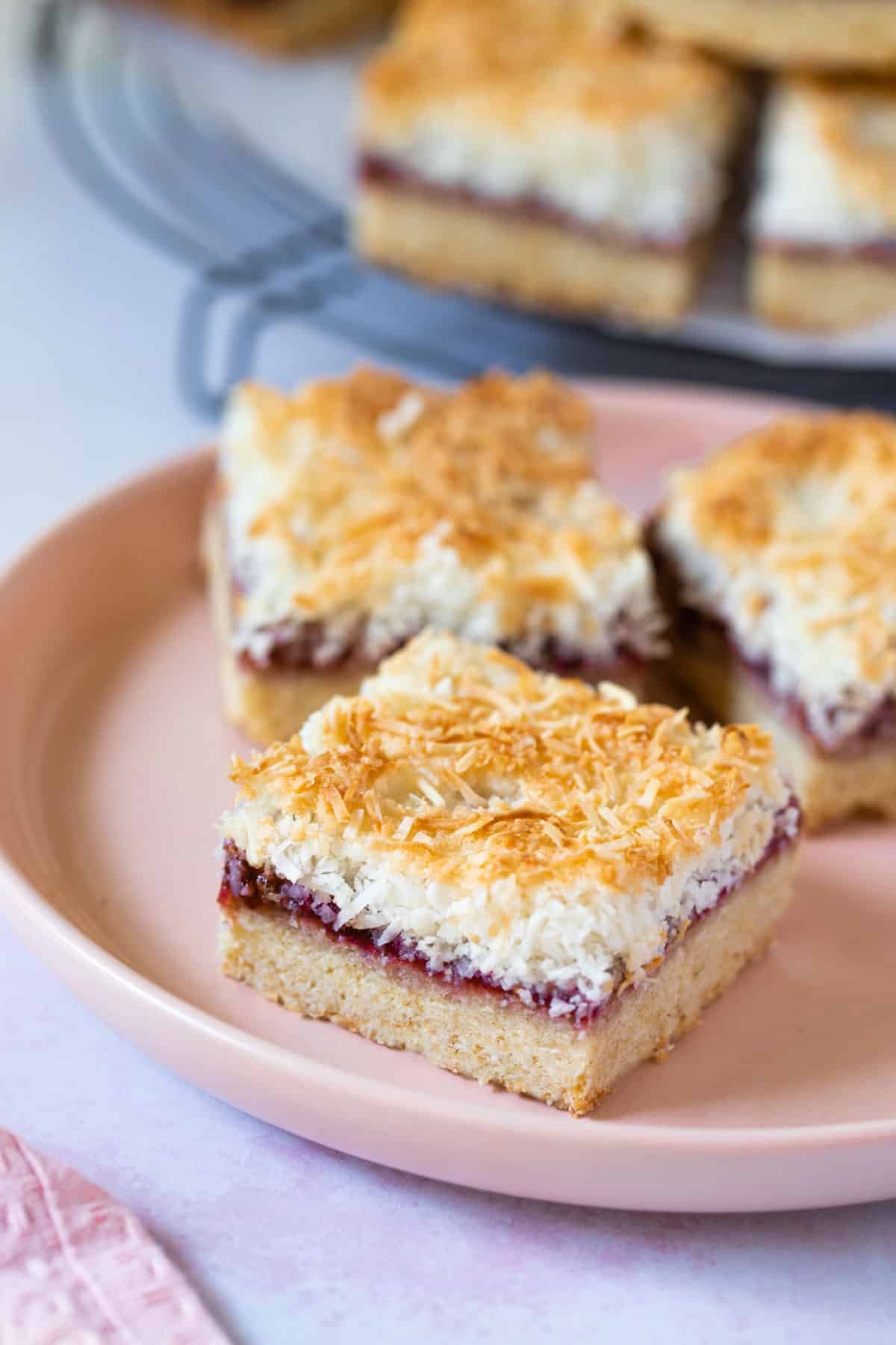 slices of coconut jam slice, arranged on a plate.