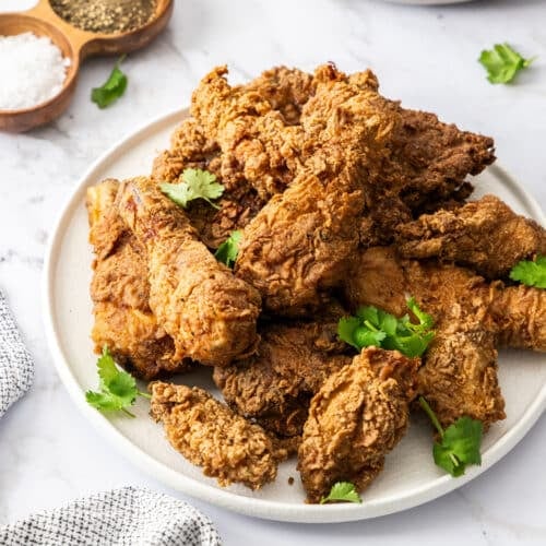 a plate of fried chicken on a table with plates and napkins.