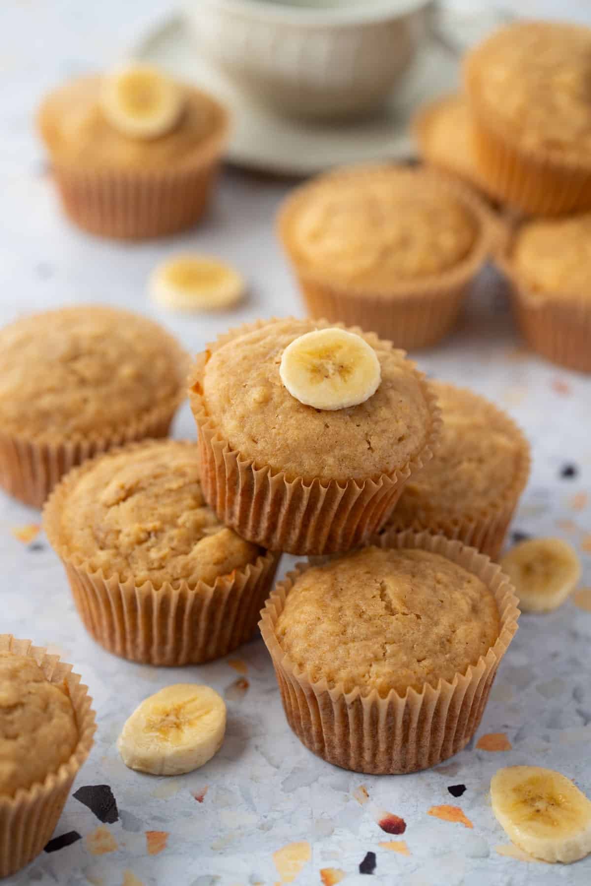 banana muffins in paper cases, arranged on a table with slices of banana.