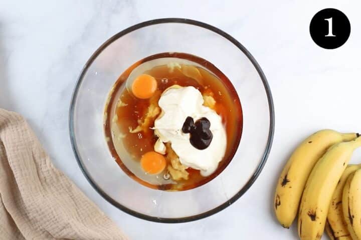 mashed banana and wet ingredients in a mixing bowl.