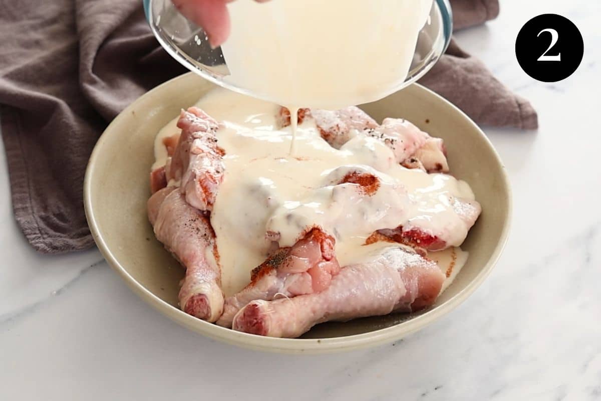 buttermilk mixture being poured over chicken pieces in a bowl.