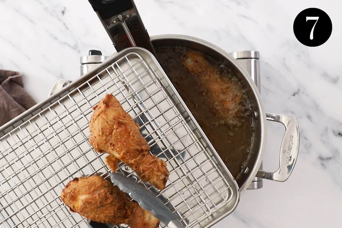 pieces of fried chicken being placed onto a wire rack.