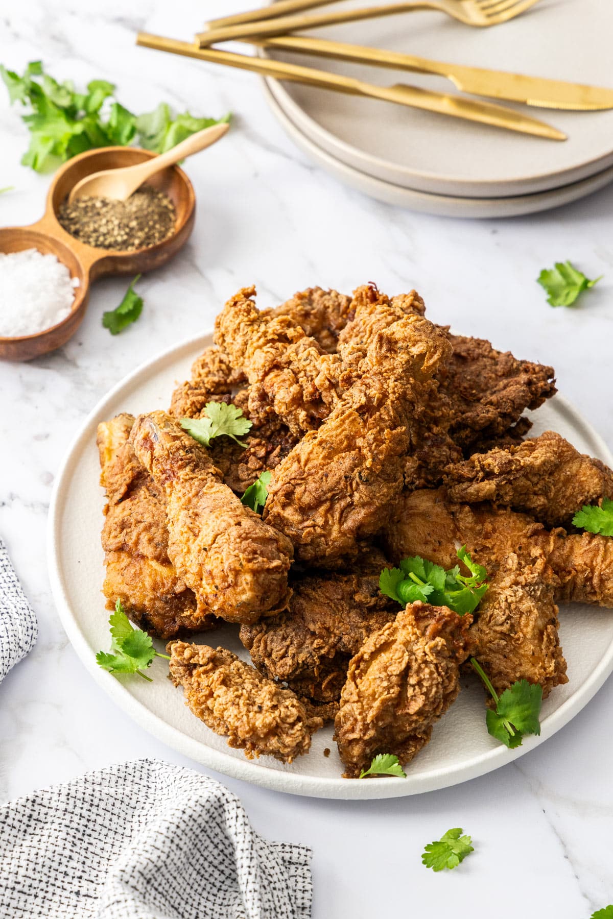 a plate of fried chicken on a table with plates and napkins.