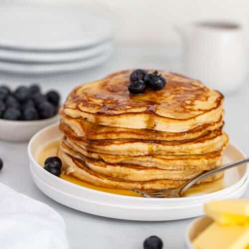 a stack of pancakes on a plate with blueberries.