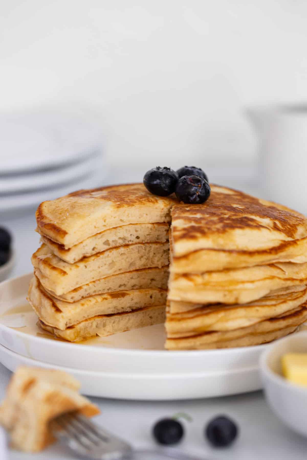 a stack of pancakes on a plate. There is a wedge cut out of the middle.